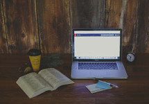 open Bible, coffee cup, and laptop on a desk 