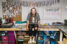 A young woman sitting in a craft room 