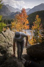 man climbing up rocks in an autumn forest 
