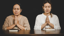 Two Asian women praying to God together.