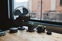 fan and house plants on a desk 