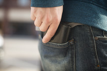 a man putting a wallet in his back pocket 