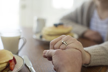 couple holding hands in prayer before breakfast.