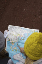 Two women in winter hats looking at a map.