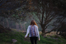 a young woman backpacking through a forest 