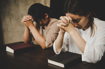 Two Asian women praying to god together in church. 