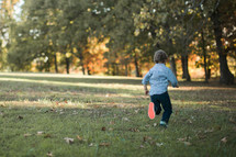 a boy child running outdoors in grass in fall 