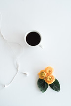 earbuds, coffee mug, and yellow flowers 