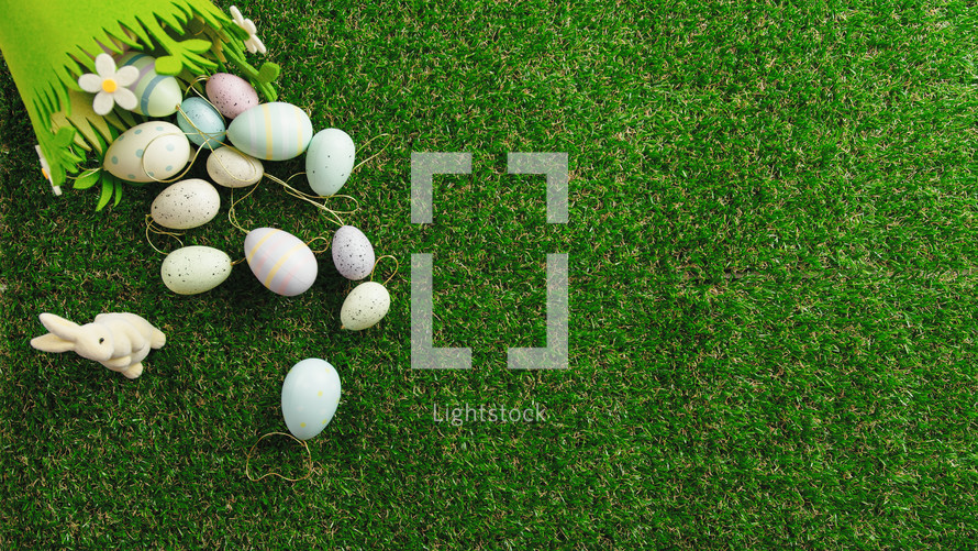 Easter background with decorated eggs and bunny decoration on grass