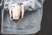 homeless woman with dirty hands holding a cup 