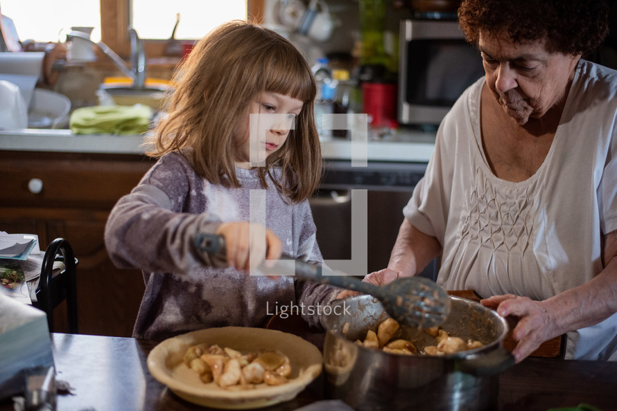 Little girl making a pie with her grandmother