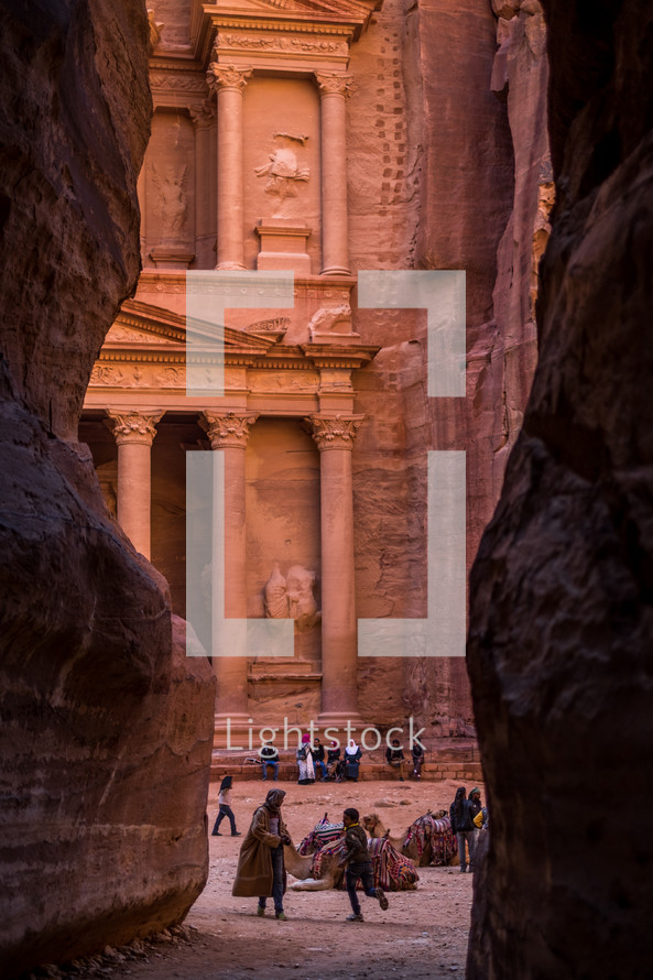 Petra: ancient temple carved into red rock with tourists 
