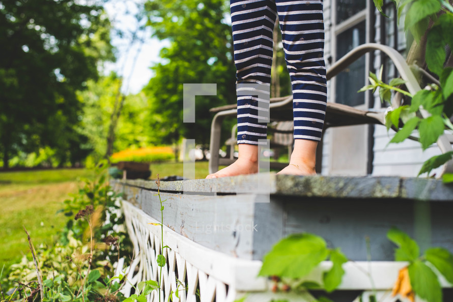 feet of a boy in pj's standing on a porch 