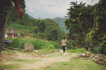 man walking down a dirt road into a village 