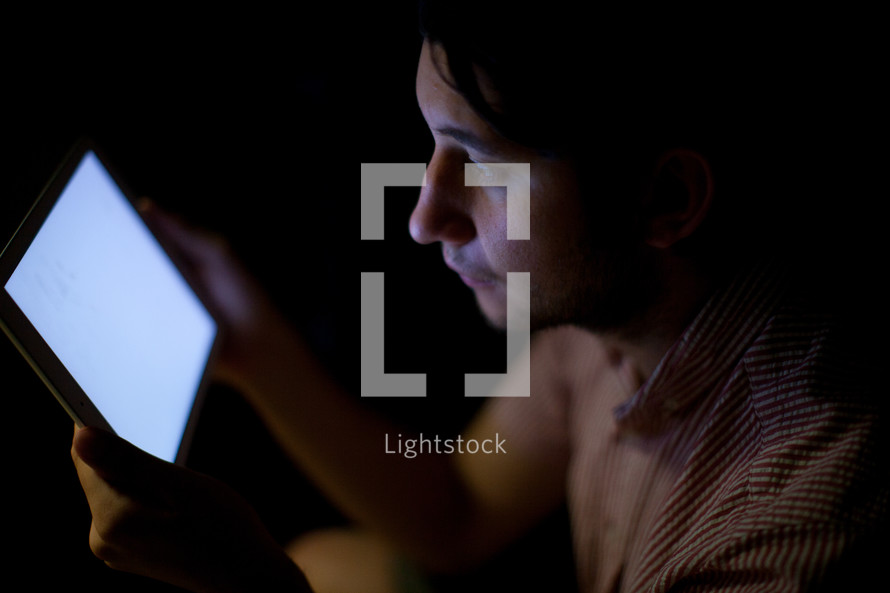 Light from an electronic tablet illuminating a man's face.