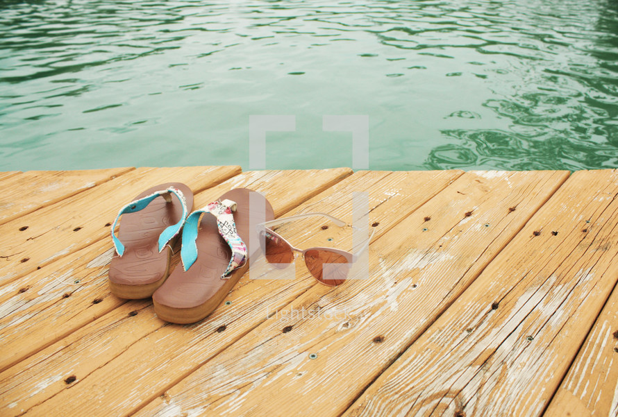 flip flops and sunglasses on a wood dock 
