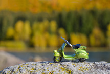Small retro green scooter toy on a rock,