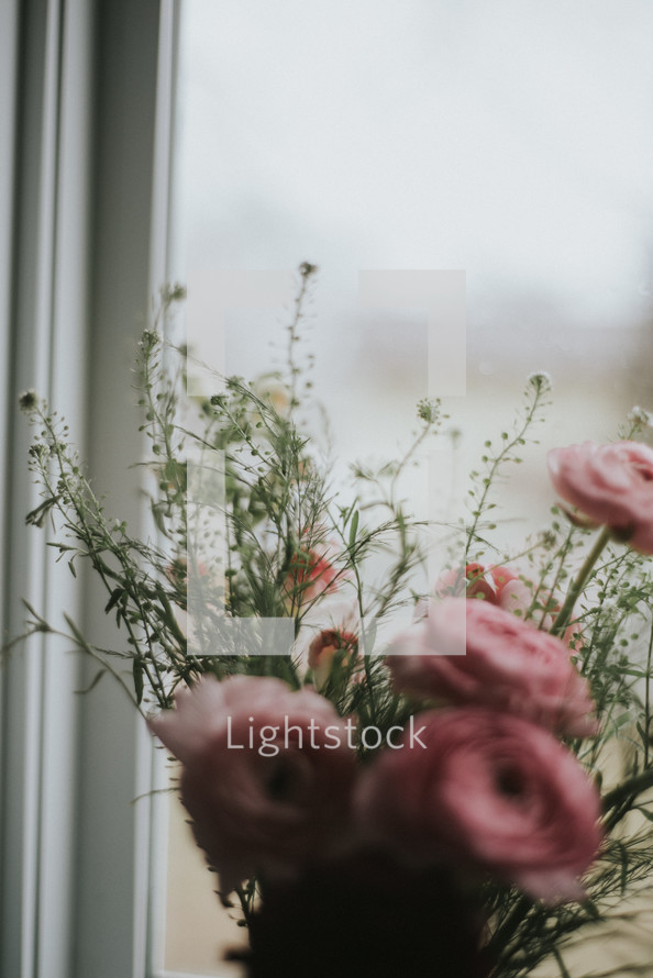 vase of red and pink flowers in a window 