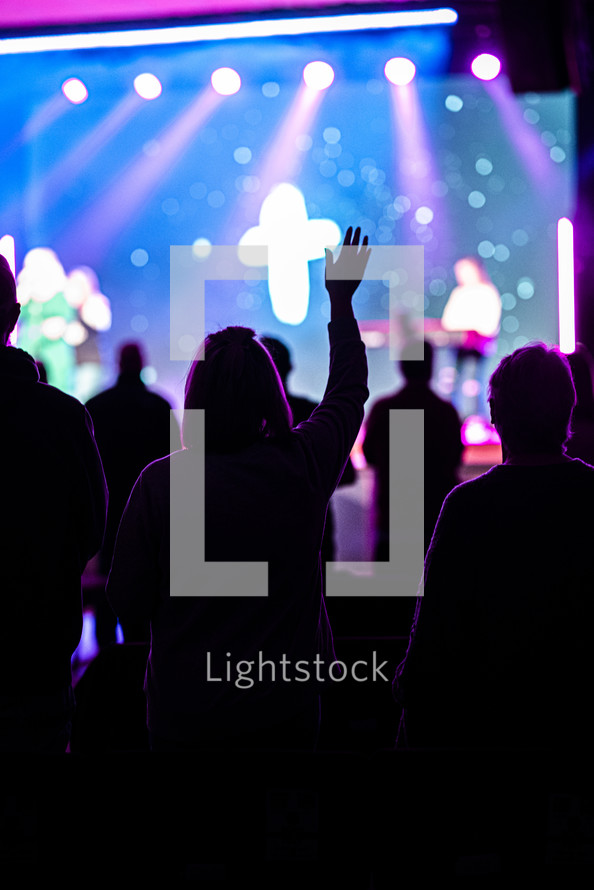 silhouettes of people at a worship service with hands raised 