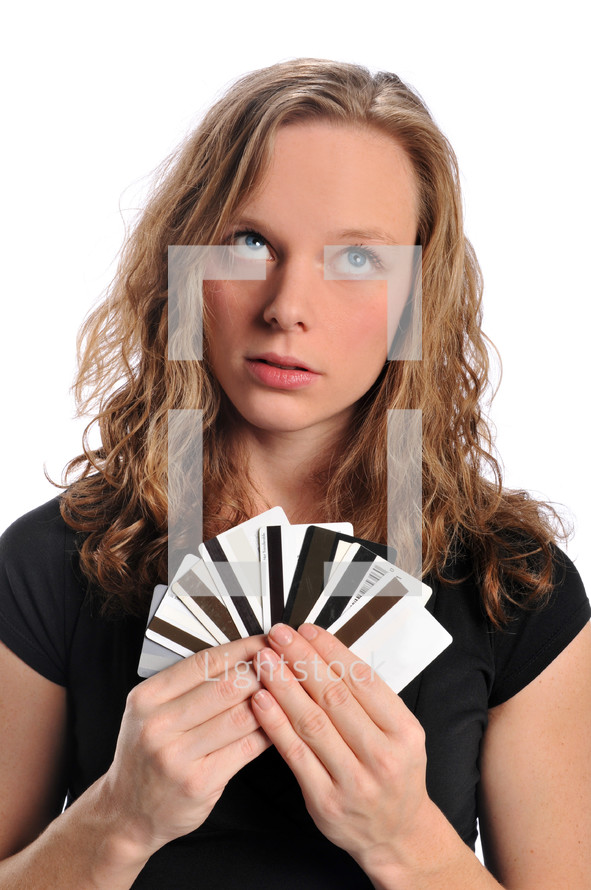 A girl looking up and holding credit cards like playing cards.