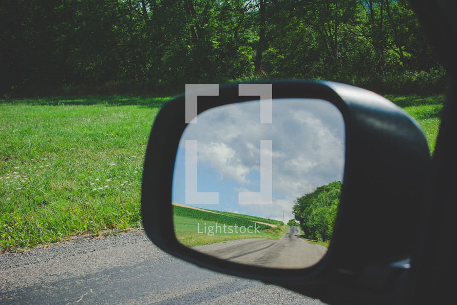 view of a rural road in the rearview mirror 