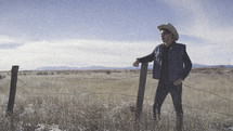 cowboy standing in a pasture 