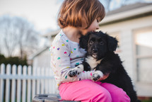toddler girl hugging a puppy 