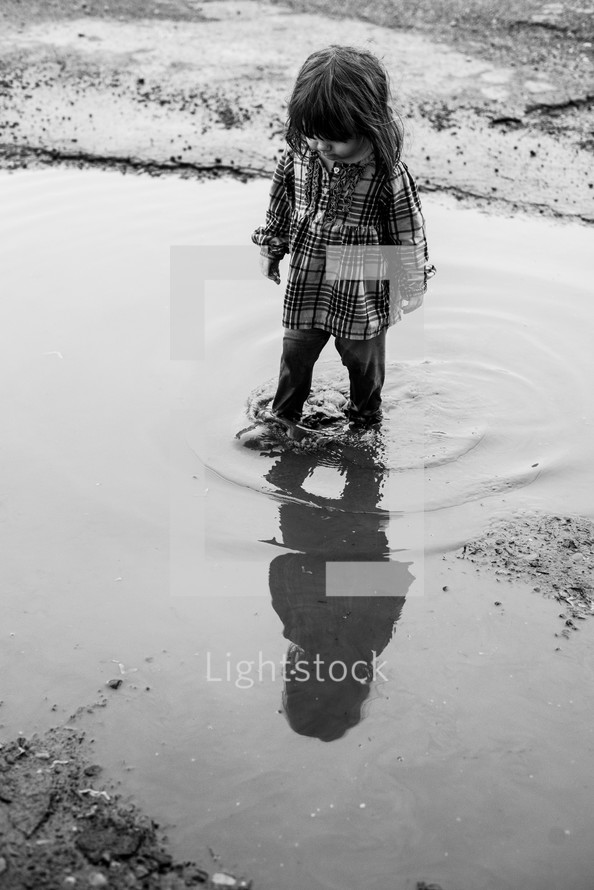 a little girl standing in a puddle 