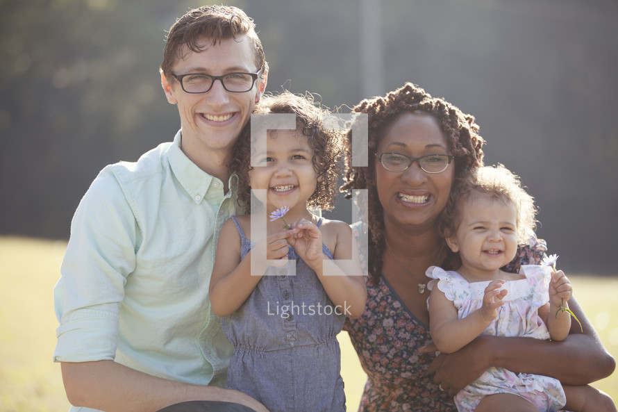 Happy multi-racial family smiling outdoors.