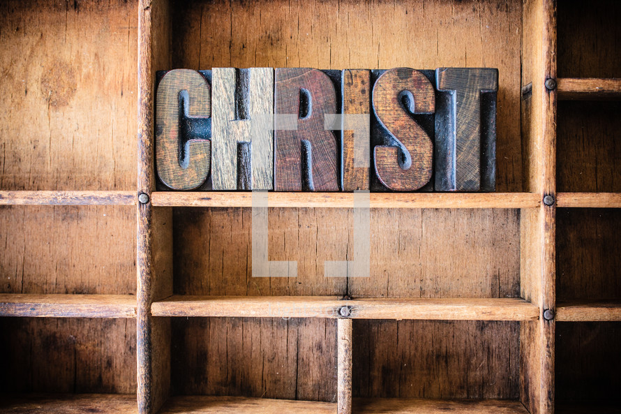 Wooden letters spelling "Christ" on a wooden bookshelf.