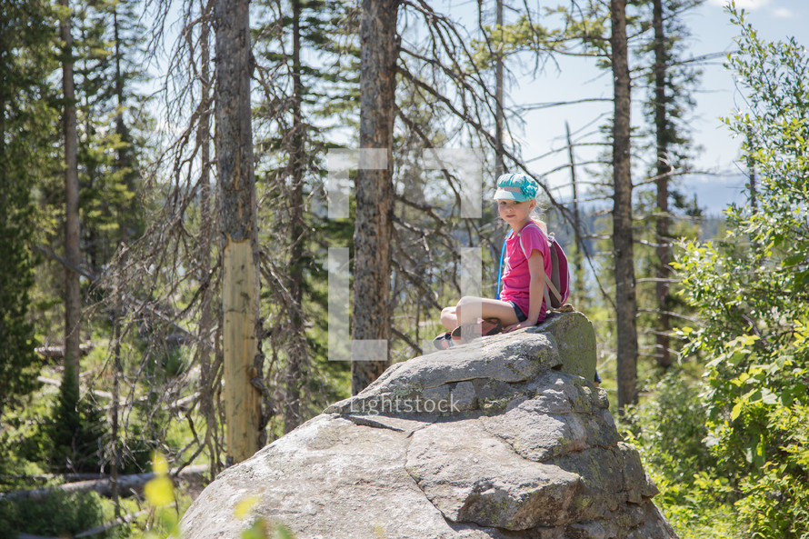 a little girl sitting on a rock 