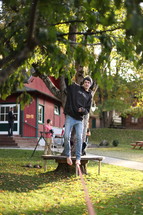 man balancing on a pole with hanging from a tree 