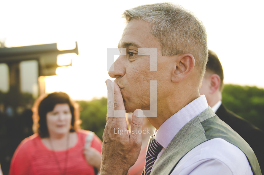 a groom blowing a kiss to his bride 