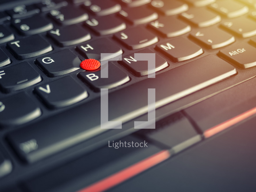 red pointing stick of on a laptop keyboard