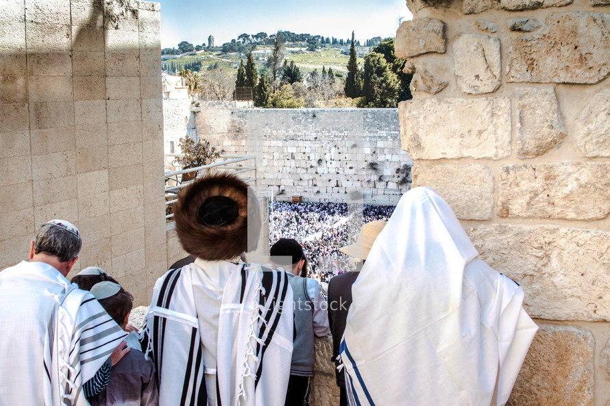 Orthodox Jews looking down at people praying at the Wailing Wall during a Jewish holiday.
