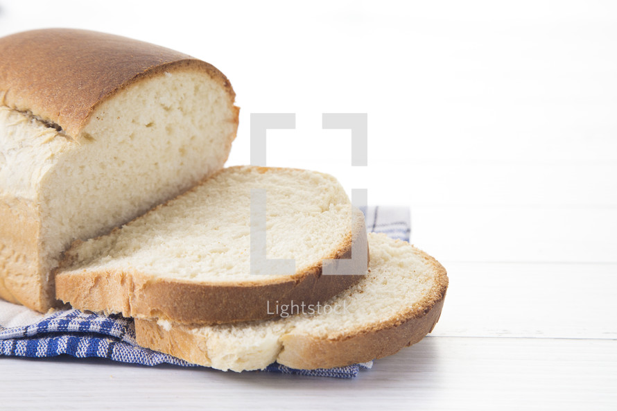 Freshly Baked Loaf of Homemade White Bread Sliced on a White Table