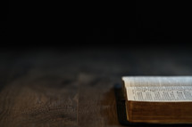 Open bible on a table with a black background