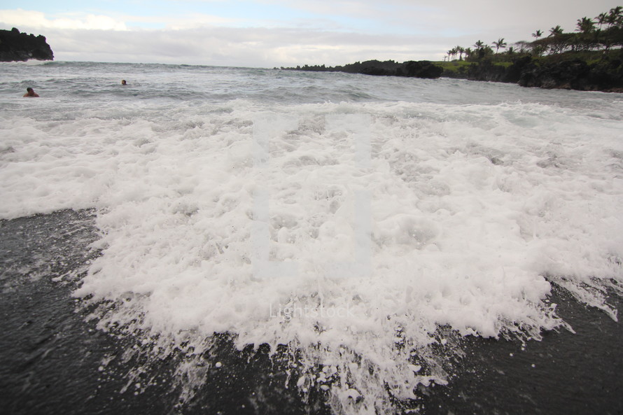 tide washing onto a black sand beach 