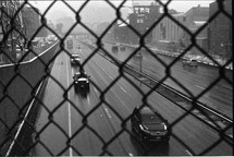 A busy highway seen through a chain link fence.