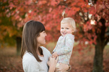 a mother and daughter standing outdoors in fall 