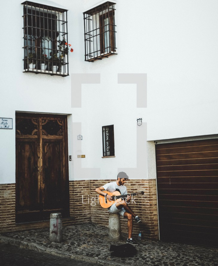 a man playing a guitar in an alley 