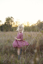 a toddler girl twirling her dress in tall grasses 