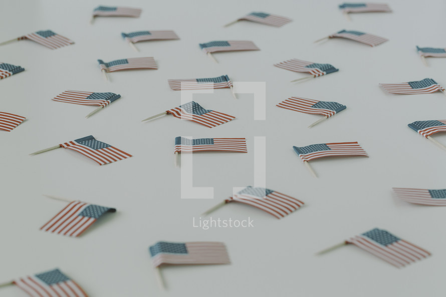 Small American flags scattered on a white surface.