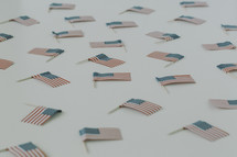 Small American flags scattered on a white surface.