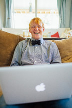 young man with a bow tie with a laptop in his lap 