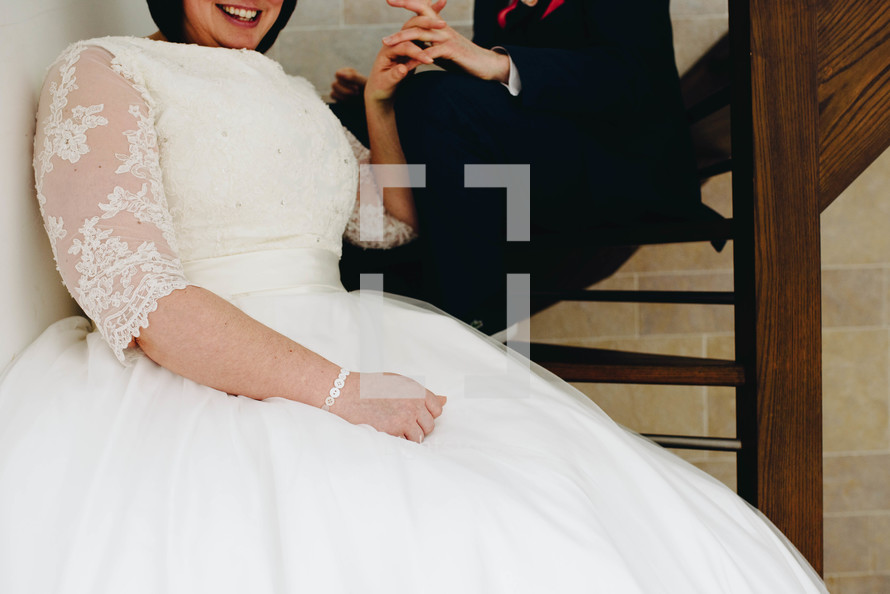 bride and military groom holding hands sitting on steps 