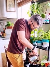 a man watering houseplants 