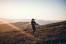 a girl standing on a mountaintop at sunrise 