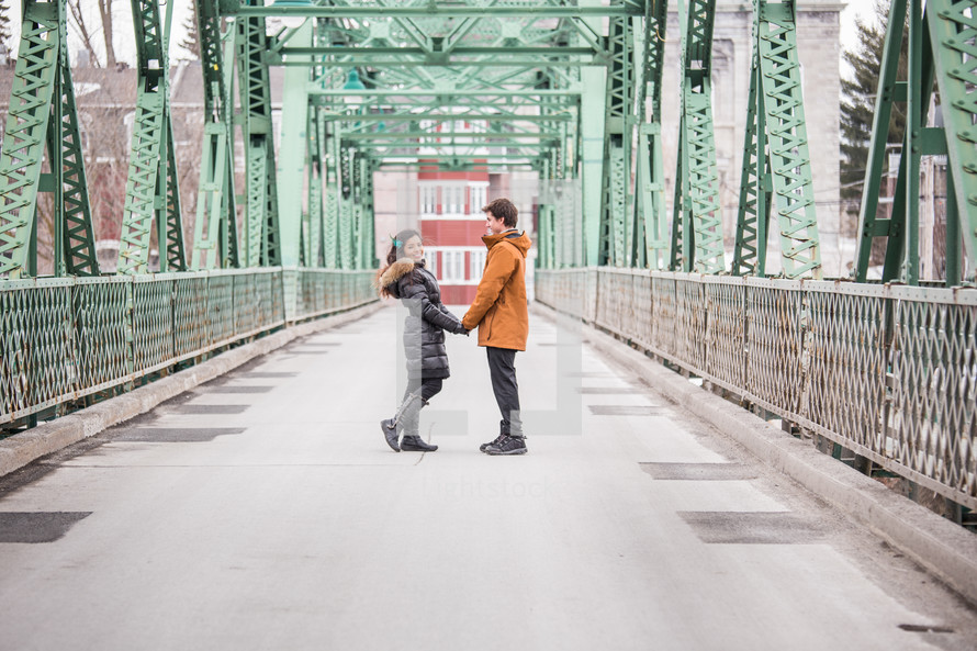 a couple holding hands on a bridge 
