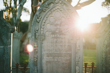 Sun shining on an ornate tombstone in a cemetery.